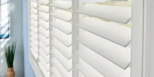A close up of the window blinds with white shutters.